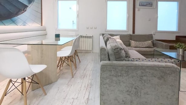 Ein modernes Wohnzimmer mit einem Glastisch, einem grauen Sofa und einer Wendeltreppe.