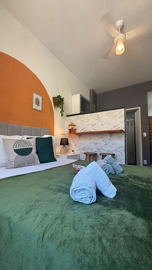 Et moderne soveværelse med en seng, ventilator i loftet og bagplade i marmor.