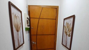 A hallway with a wooden door, two framed floral paintings on the walls, and a tiled floor. - Crown Casa Copacabana 1 (Rio de Janeiro)
