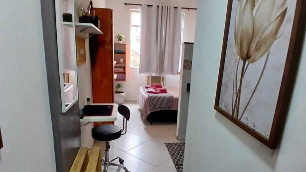 A narrow hallway leading to a bedroom with a bed, a desk, and a chair. There is a ceiling fan and a framed picture on the wall. - Crown Casa Copacabana 1 (Rio de Janeiro)