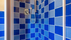 A bathroom with blue-tiled walls and a shower area.