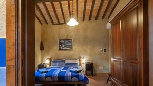 A bedroom with a wooden bed, two bedside tables with lamps, a wooden wardrobe, and a painting on the wall.