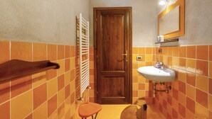 A bathroom with orange tiles, a wooden door, a white sink, and a towel rack.