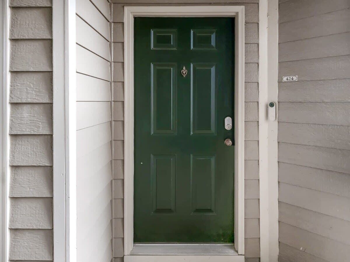 Une porte d’entrée verte avec un cadre blanc, une petite boîte aux lettres et le numéro de maison 424.