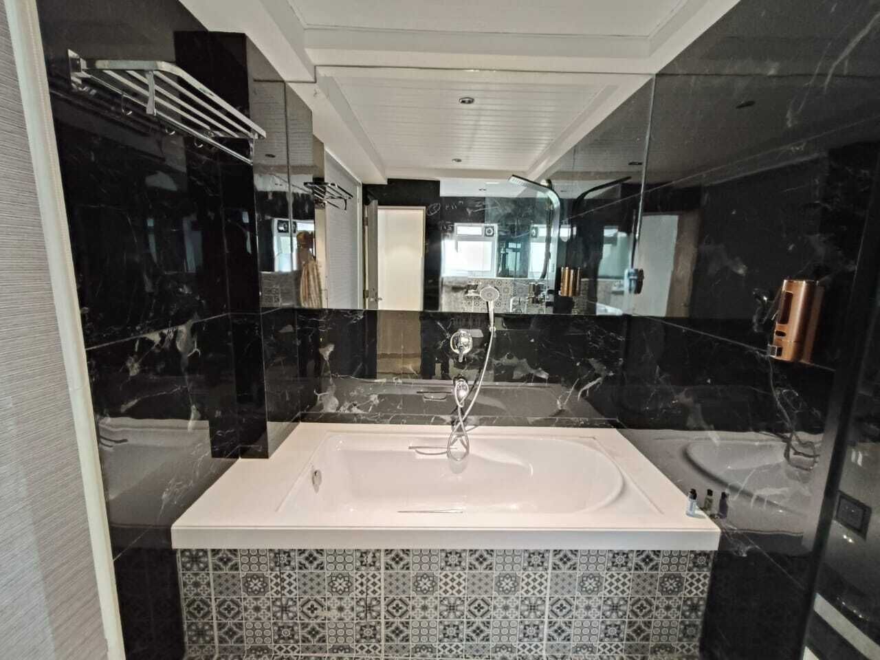 A modern bathroom with a large bathtub, a shower, and a glass-enclosed vanity.