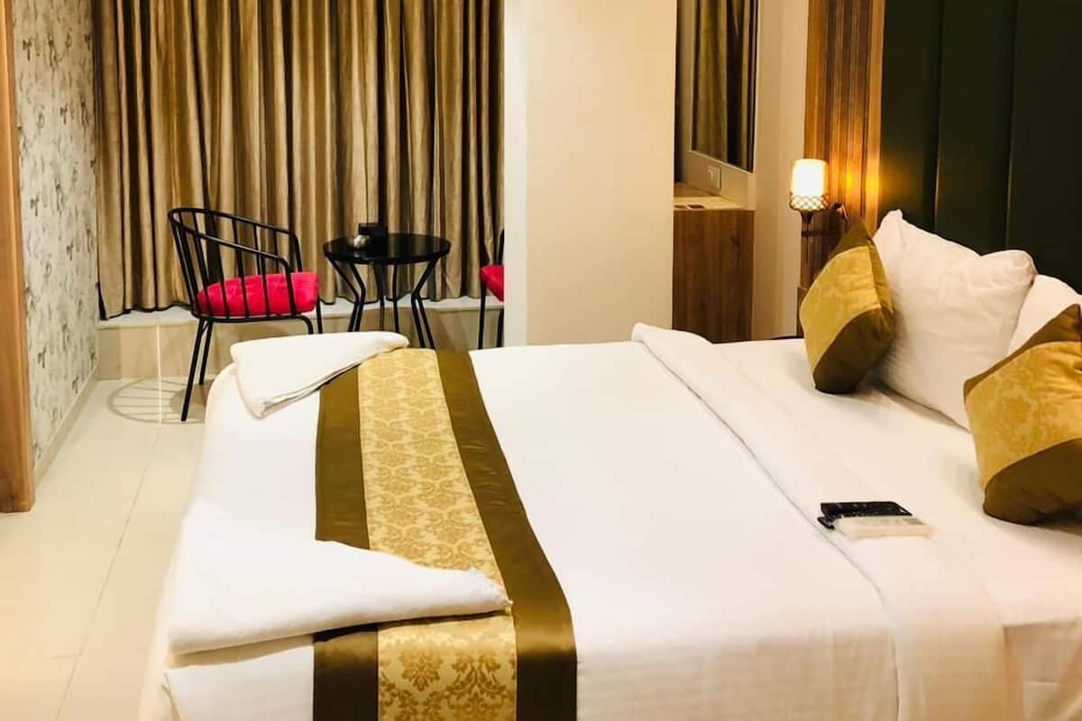 Een hotelkamer met een groot bed, een bureau, twee stoelen, een spiegel en een gordijn.