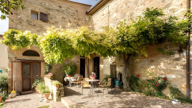 A stone building with a patio area featuring outdoor seating and potted plants. - Borghetto di San Filippo Flat with Pool (Barberino Tavarnelle)