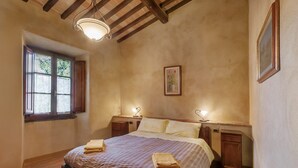A bedroom with a bed, bedside tables, a window, and a ceiling light fixture. - Borghetto di San Filippo Flat with Pool (Barberino Tavarnelle)