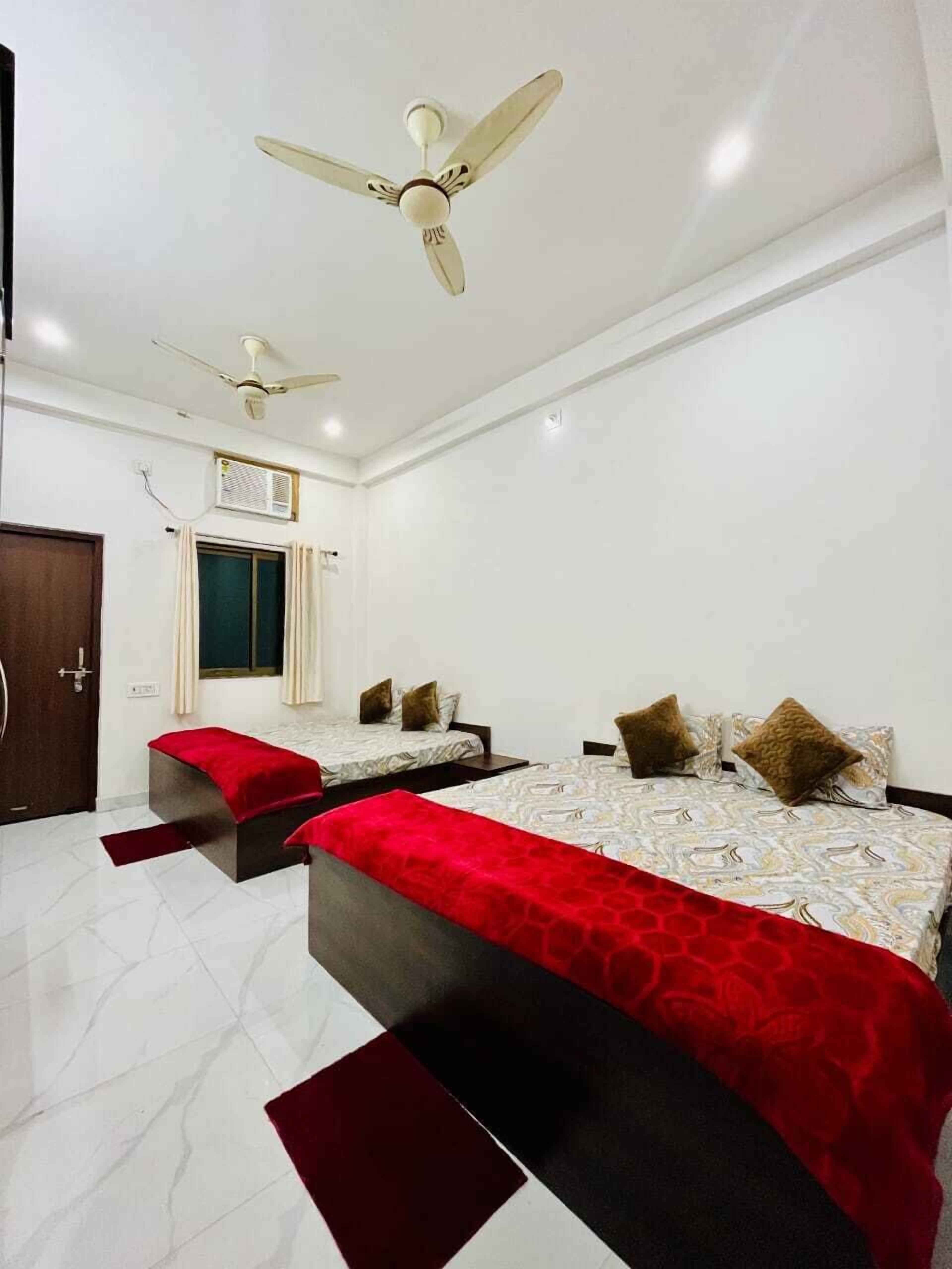 Une chambre d’hôtel avec deux lits, un ventilateur de plafond, un appareil de climatisation et une porte.