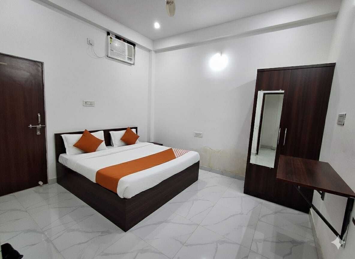 A bedroom with a bed, a wardrobe, a mirror, and a small table.