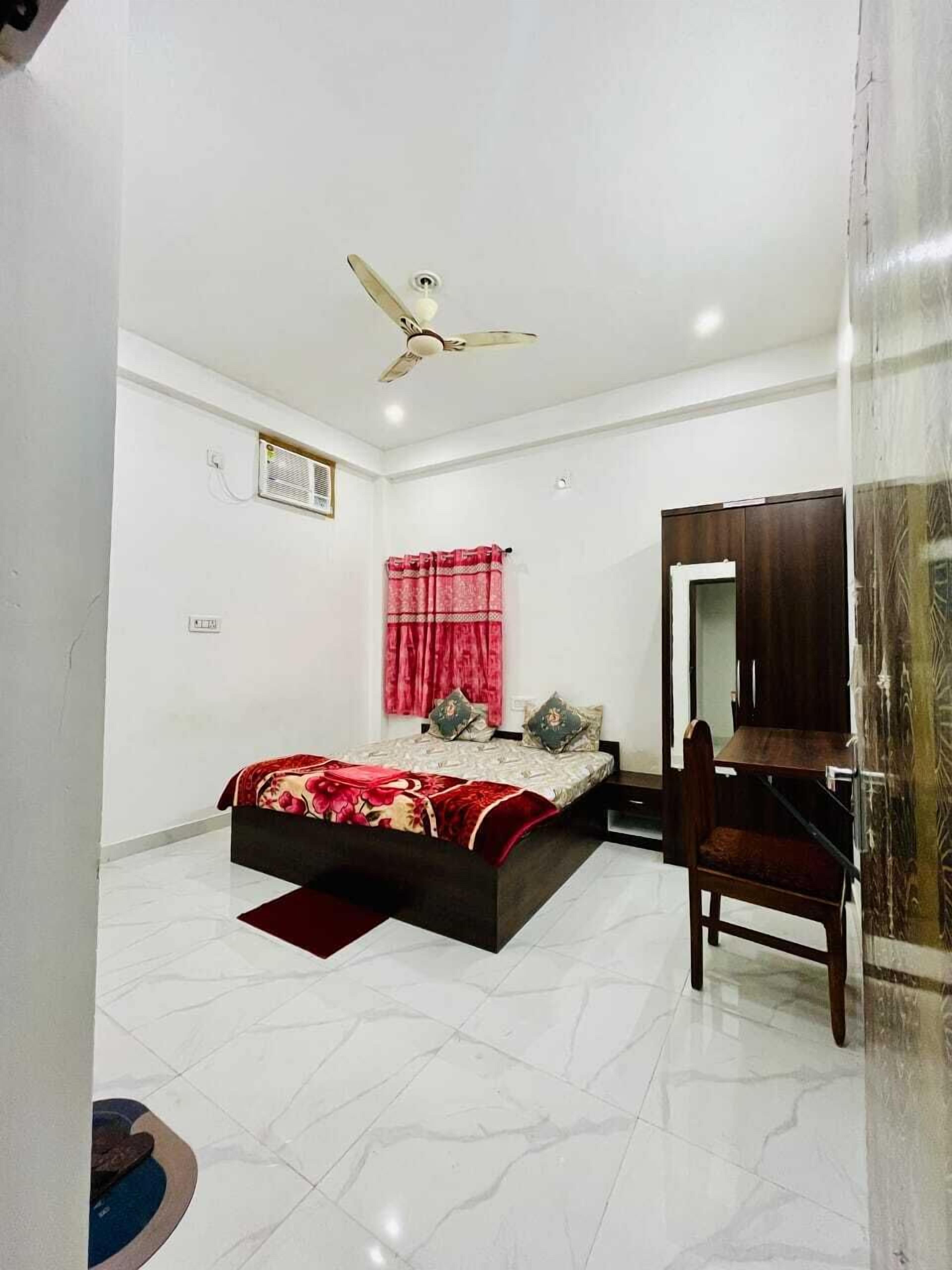 A bedroom with a bed, a ceiling fan, a wooden chair, and a mirror.