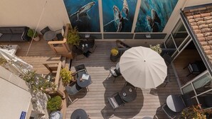 Eine Terrasse im Freien mit Holzboden, mehreren Sitzbereichen und einem großen Sonnenschirm.