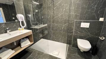 Un baño moderno con ducha, inodoro y lavamanos.
