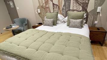 A bedroom with a large bed, a chair, a nightstand, and a wall mural.