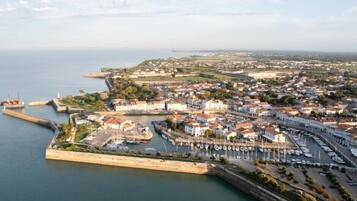 An aerial view of a coastal town with a marina, buildings, and a fortified wall.