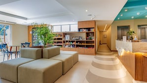 Una moderna hall d'albergo con zona salotto, reception e una grande libreria.