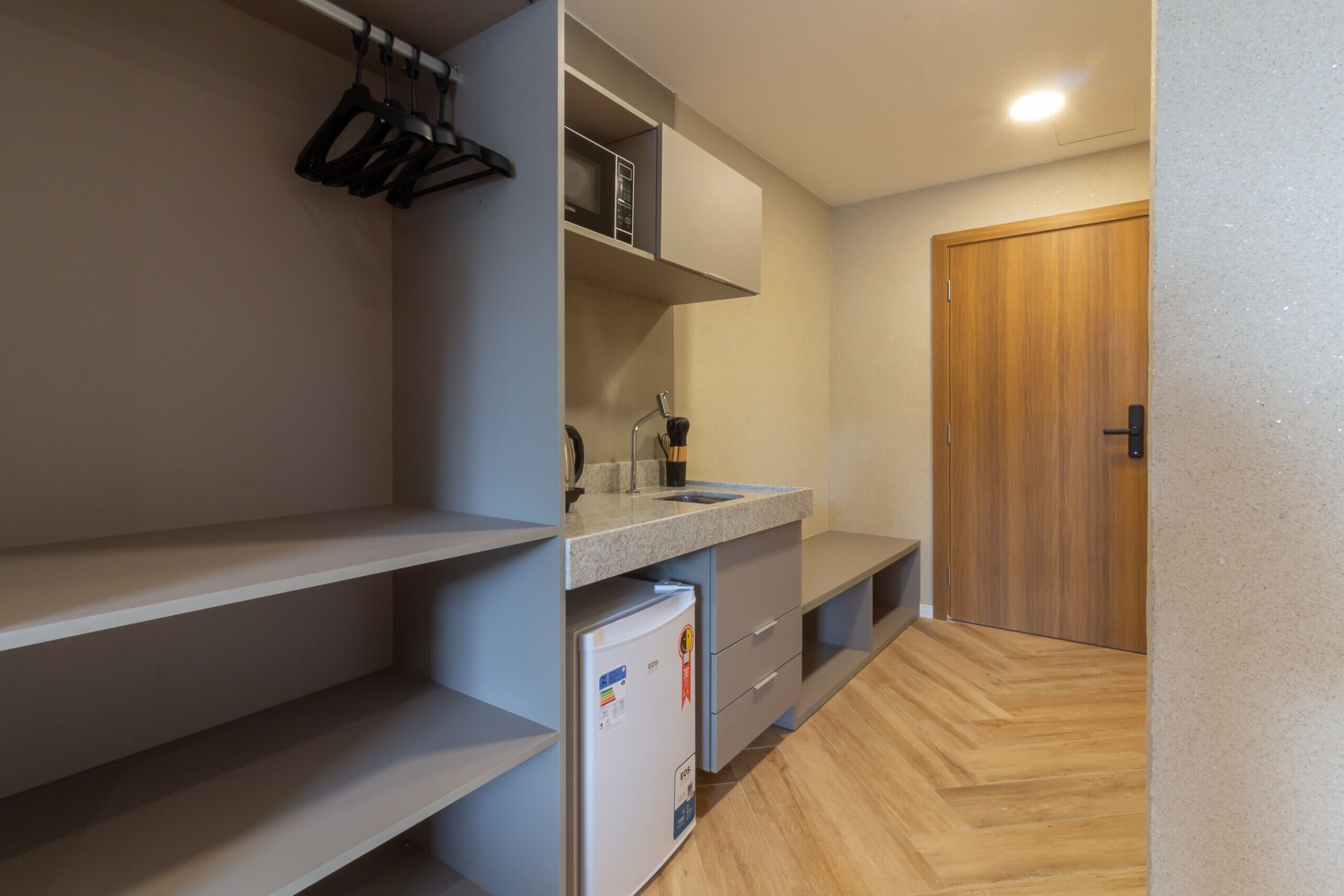 A compact kitchen with a built-in refrigerator, a sink, and a wooden door.