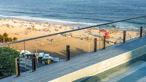 A poolside view with a beach in the background, a yellow bag, and a red cap. - Sea View and Balcony With Bathtub Q12 (Rio de Janeiro)