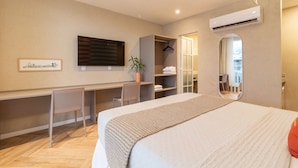 A hotel room with a bed, a desk, a chair, a mirror, and an air conditioning unit. - Sea View and Balcony With Bathtub Q12 (Rio de Janeiro)
