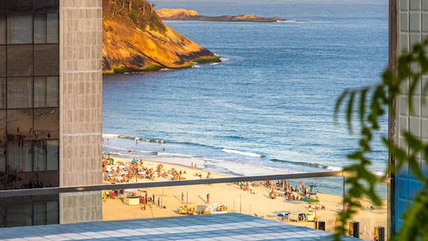 An infinity pool with a view of a beach and mountains. - Sea View and Balcony With Bathtub Q12 (Rio de Janeiro)