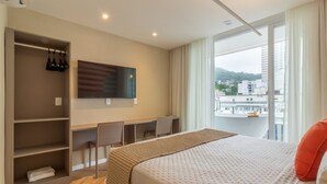 Habitación de hotel con una cama grande, un escritorio con sillas, un televisor y vistas a la ciudad.
