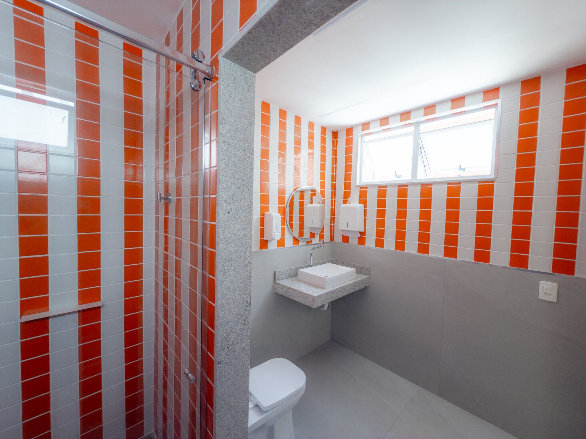 Et badeværelse med orange og hvide fliser, en hvid vask og et toilet.