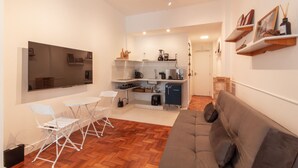 Un espacio habitable compacto con kitchenette, un sofá y una zona de comedor con sillas.