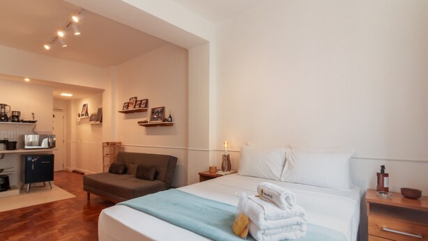 Una habitación de hotel con cama, sofá, kitchenette pequeño y baño.