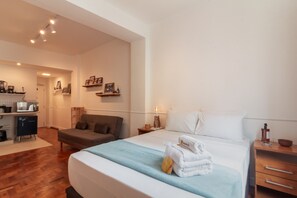 Ein Hotelzimmer mit Bett, einer Sitzecke, einer kleinen Küchenzeile und einem Badezimmer.