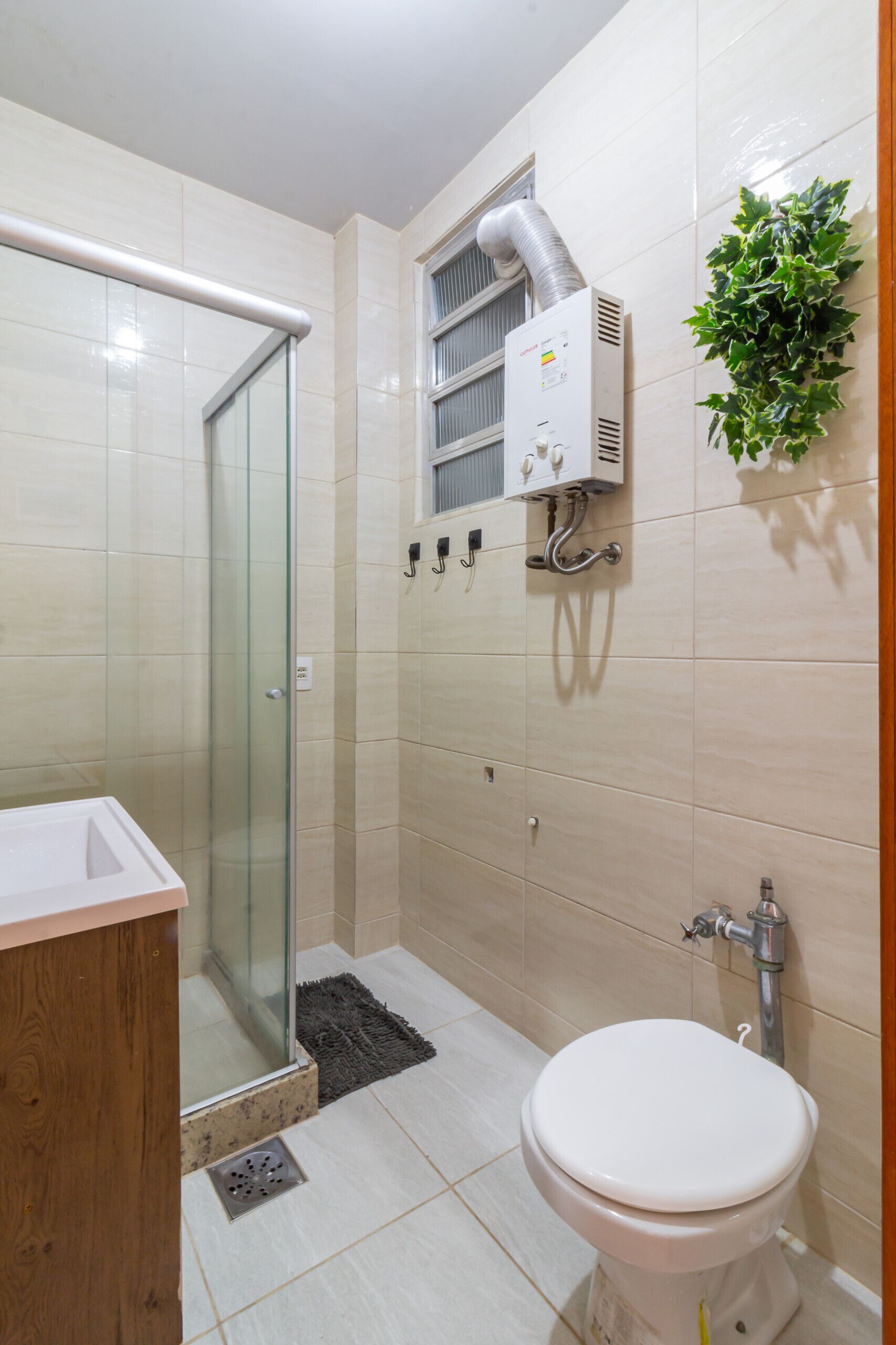 Un baño moderno con cabina de ducha de vidrio, inodoro blanco y sistema de ventilación integrado.