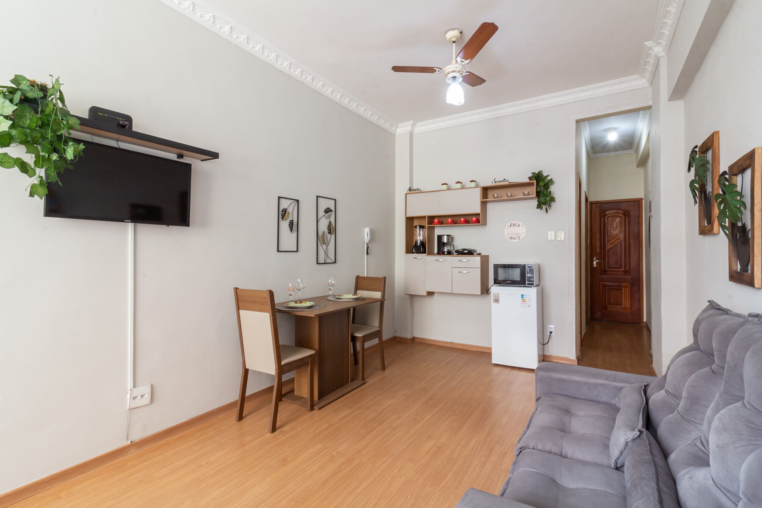 A compact living space with a dining area, kitchenette, and a grey sofa.