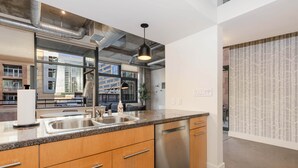 A modern kitchen with granite countertops, stainless steel appliances, and a large window offering a view of the cityscape. - Union Station downtown and gameday retreat! (Denver)