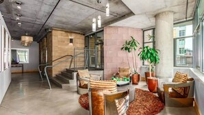 A spacious lobby with a concrete ceiling, a staircase, and seating areas with potted plants. - Union Station downtown and gameday retreat! (Denver)