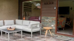 Un espace patio aménagé avec un canapé blanc, une petite table ronde et un vase décoratif.