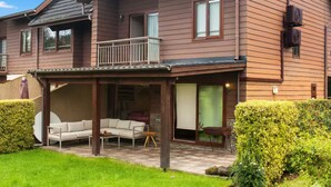Une maison à deux étages dotée d’un patio couvert, d’un balcon et d’un jardin bien entretenu.