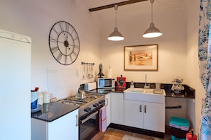 Une cuisine équipée d’une cuisinière, d’un four à micro-ondes, d’un évier et d’une grande horloge murale.