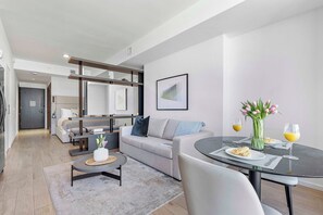 Un salon moderne avec un canapé, une table basse et une table à manger pour deux personnes.