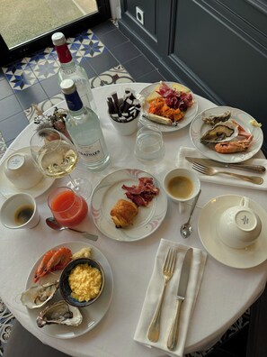 A dining table with plates of food, a bottle of liquor, and various glasses. - HR Hôtel & Spa Marin (La Flotte)