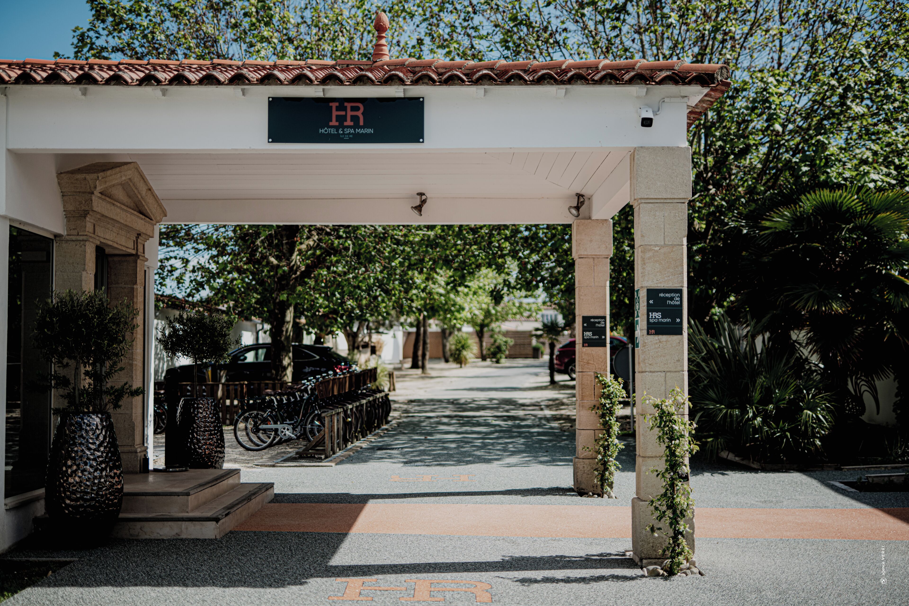 A hotel entrance with a tiled roof, a signboard, and a pathway leading to the entrance.