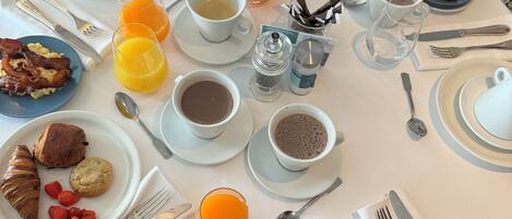 Una mesa de desayuno con diversos alimentos, bebidas y utensilios para comer.