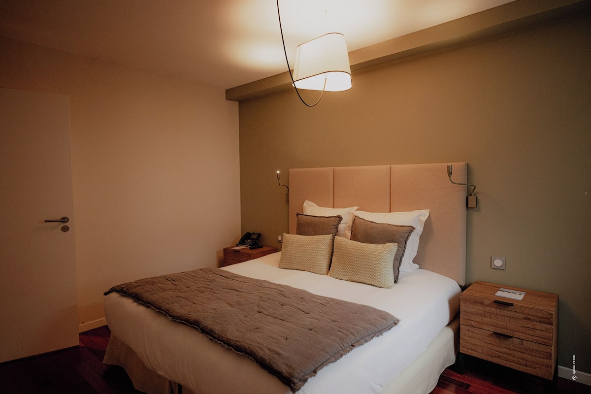 A bedroom with a bed, bedside tables, a lamp, and a door.
