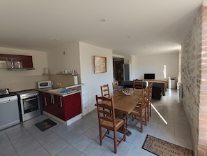 A modern kitchen with a dining area, a microwave, a stove, and a television. - Holiday Home 'Le Gîte Du Vieux Mûrier Côté Sud' with Private Garden, Wi-Fi and Air Conditioning (Saint-Jean de Serres)