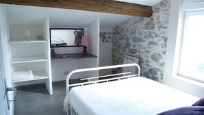 Een slaapkamer met een bed, een inbouw bureau, een spiegel en een stenen muur.