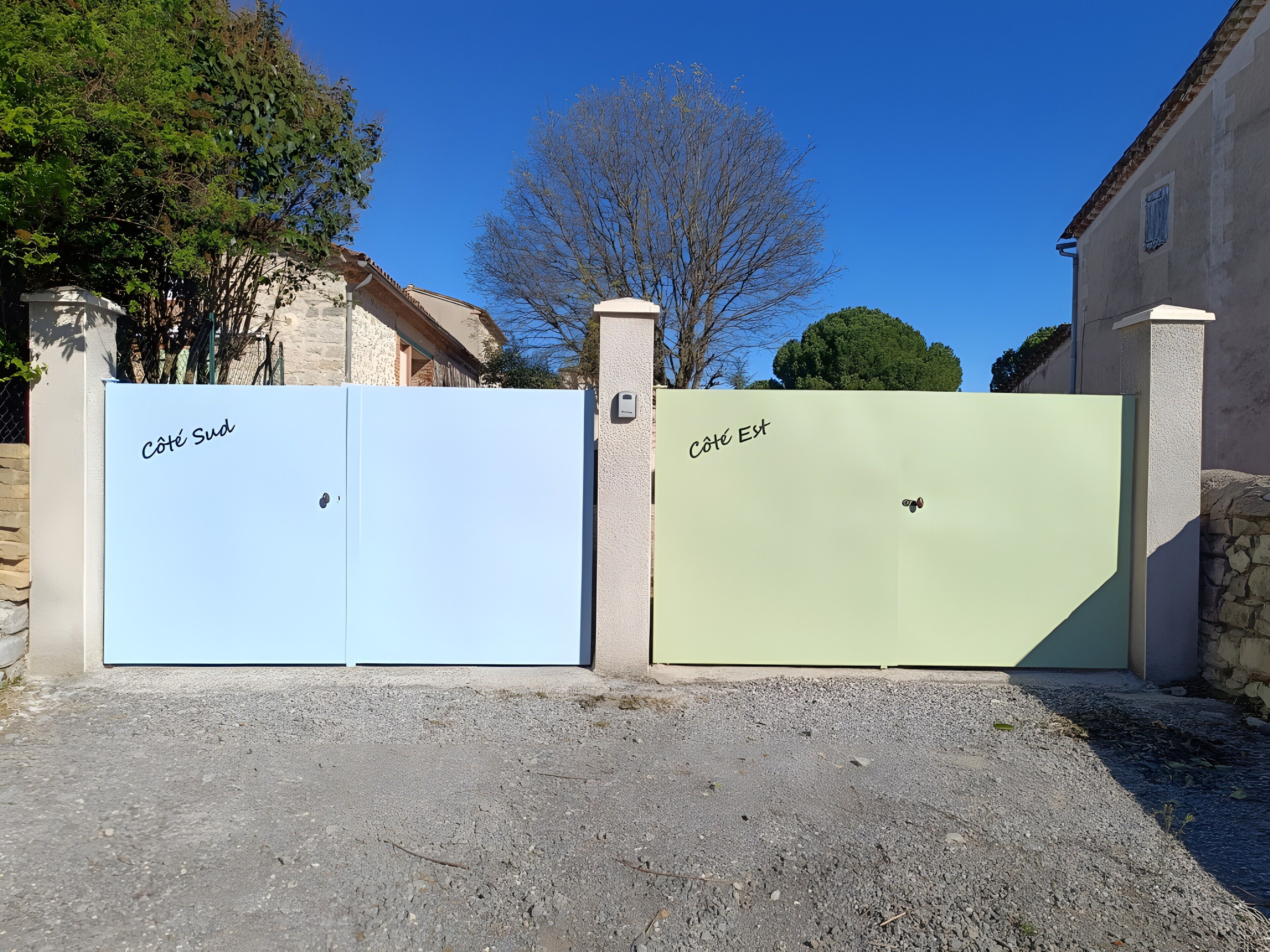 Deux portails portant les inscriptions « Côte Sud » et « Côte Est », avec un bâtiment et des arbres en arrière-plan.