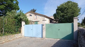 Una casa in pietra con tetto a tegole, un cancello e un vialetto sterrato.
