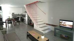 Un soggiorno moderno con scale, una cucina e un televisore.