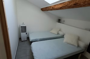 A small, clean room with two beds, a ceiling fan, and a window. - Holiday Home 'Le Gîte Du Vieux Mûrier Côté Est' with Private Garden, Wi-Fi and Air Conditioning (Saint-Jean de Serres)