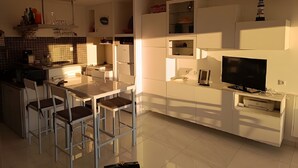 A modern kitchen with a dining area, built-in appliances, and a flat-screen TV. - “Sea & Sun” Apartment with Private Terrace (Port Camargue)