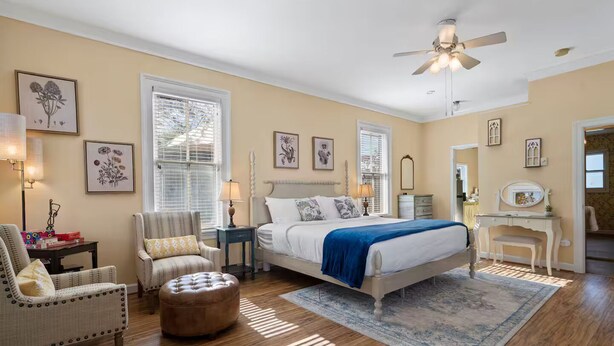 A bedroom with a bed, two chairs, a nightstand, a dresser, and a vanity with a mirror. - Shenandoah Valley Cottage (Stanley)