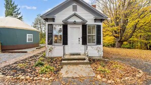 A small white house with a front porch, a mailbox, and a mailbox slot. - Shenandoah Valley Cottage (Stanley)